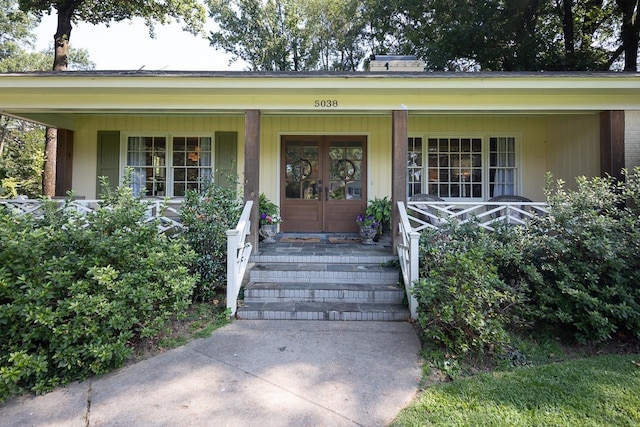 view of exterior entry with covered porch and french doors