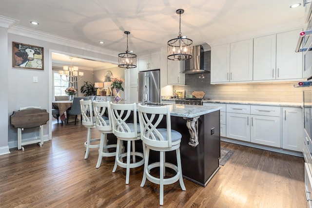 kitchen featuring white cabinetry, high end fridge, wall chimney exhaust hood, and an island with sink