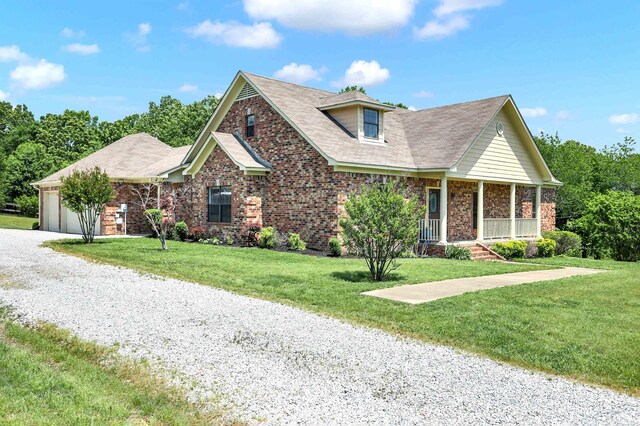 view of front of property with covered porch, a front lawn, and a garage