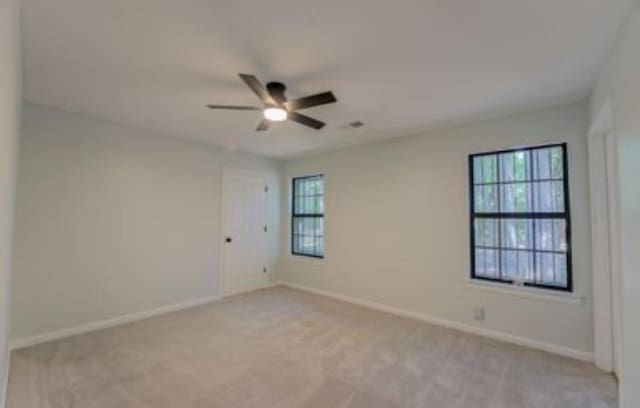 empty room with ceiling fan and light colored carpet