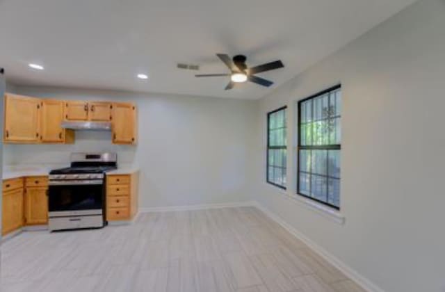 kitchen with ceiling fan, stainless steel range, and light brown cabinets