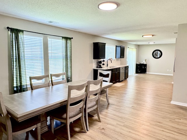 dining space featuring a textured ceiling, light hardwood / wood-style floors, and sink