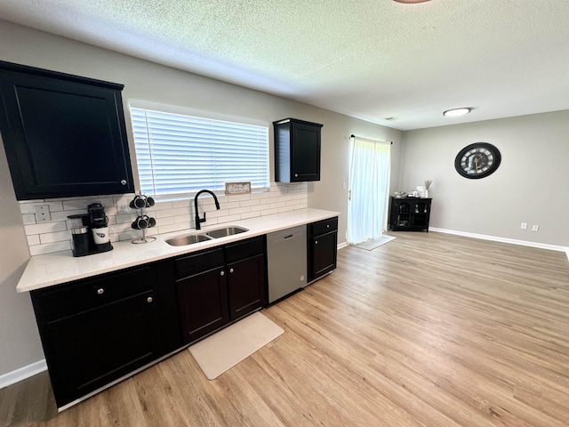 kitchen featuring tasteful backsplash, a textured ceiling, sink, light hardwood / wood-style flooring, and dishwasher