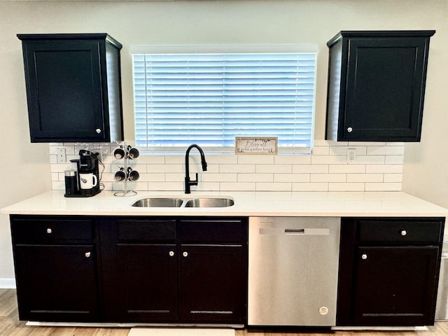 kitchen with stainless steel dishwasher, decorative backsplash, light hardwood / wood-style floors, and sink