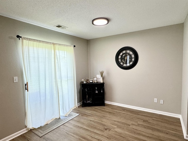 empty room with a textured ceiling and hardwood / wood-style flooring