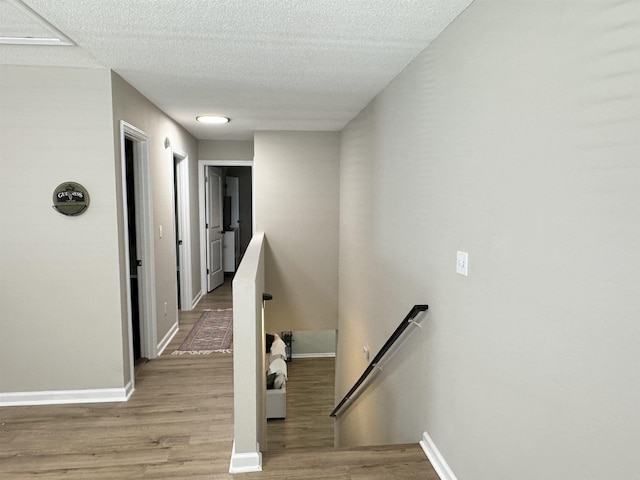 stairway with a textured ceiling and hardwood / wood-style flooring