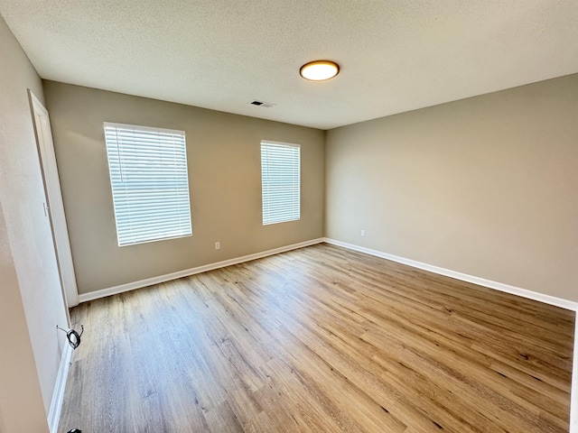 unfurnished room with a textured ceiling, light hardwood / wood-style flooring, and a wealth of natural light