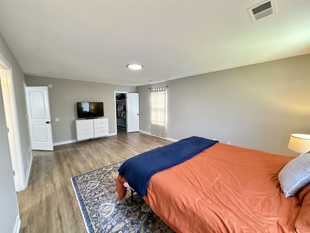 bedroom featuring a walk in closet, a closet, and hardwood / wood-style flooring