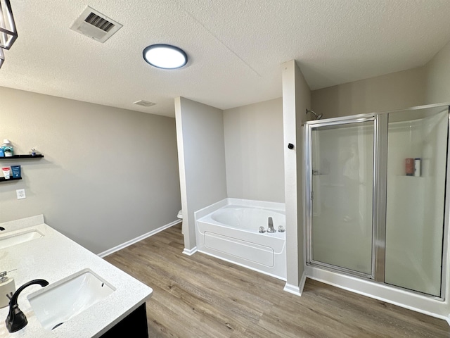 full bathroom with separate shower and tub, hardwood / wood-style floors, a textured ceiling, toilet, and vanity