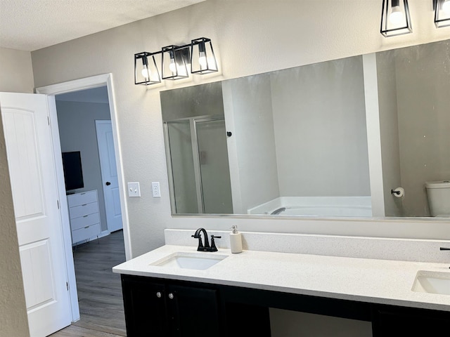 bathroom with hardwood / wood-style floors, vanity, a shower with door, toilet, and a textured ceiling