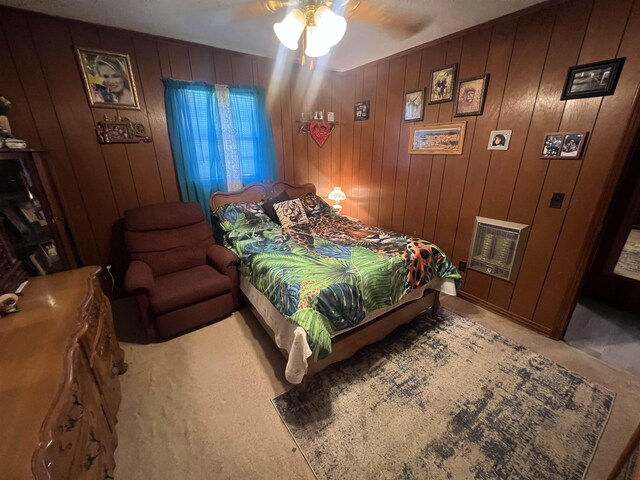 carpeted bedroom featuring ceiling fan, heating unit, and wood walls