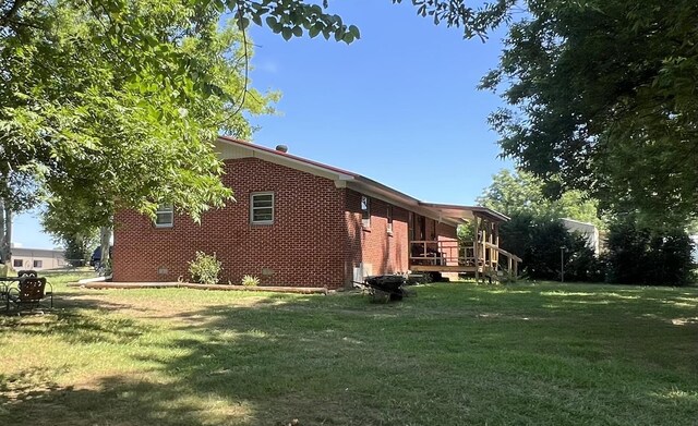 view of side of property featuring a lawn and a wooden deck