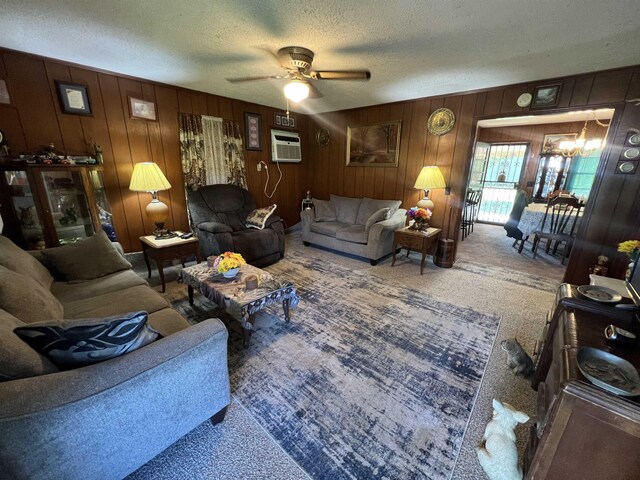 living room with wooden walls, ceiling fan with notable chandelier, a textured ceiling, and carpet flooring