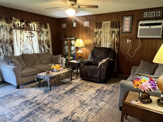 living room featuring ceiling fan, a wall mounted AC, wood walls, and a textured ceiling