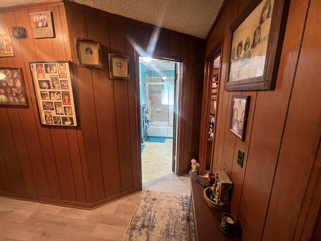 corridor featuring a textured ceiling and wooden walls