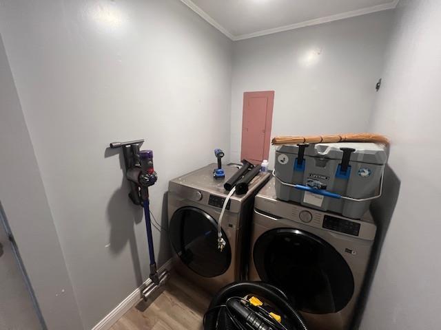 clothes washing area featuring washer and dryer, light wood-type flooring, and crown molding