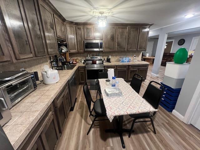 kitchen featuring appliances with stainless steel finishes, light wood-type flooring, dark brown cabinets, and sink