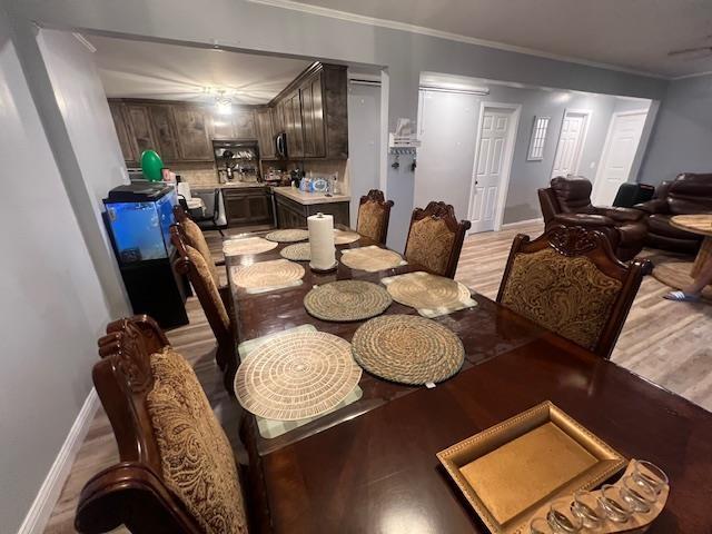 dining area with light wood-type flooring and ornamental molding