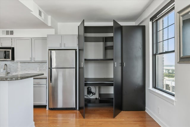 kitchen with decorative backsplash, sink, stainless steel appliances, and light hardwood / wood-style flooring