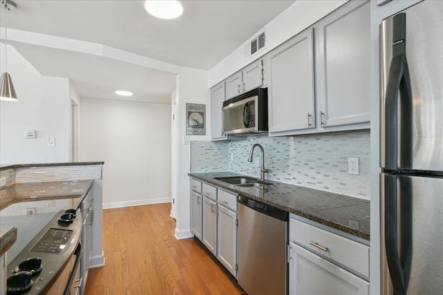 kitchen with backsplash, sink, gray cabinets, appliances with stainless steel finishes, and light hardwood / wood-style floors