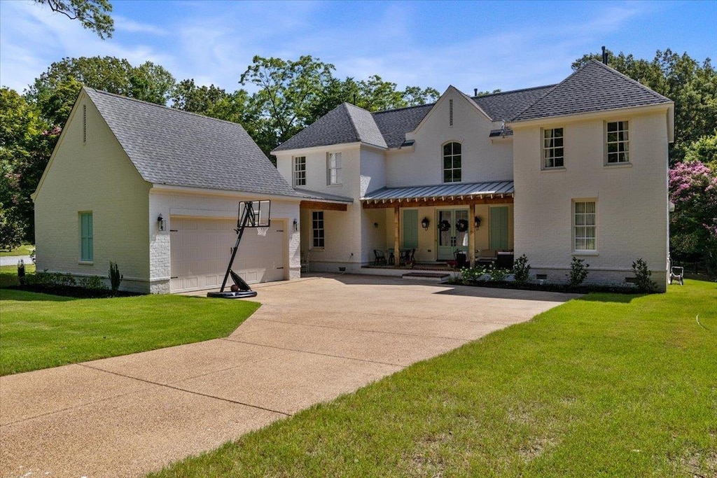 view of front of property featuring covered porch, a front lawn, and a garage