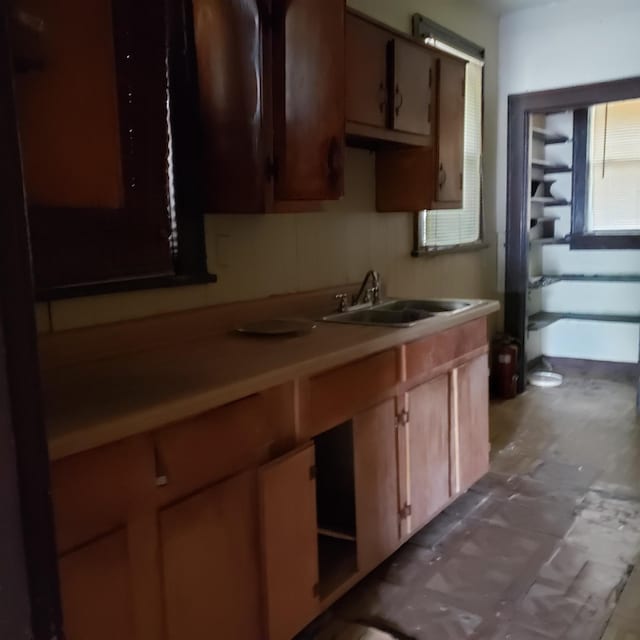 kitchen with brown cabinetry, light countertops, and a sink