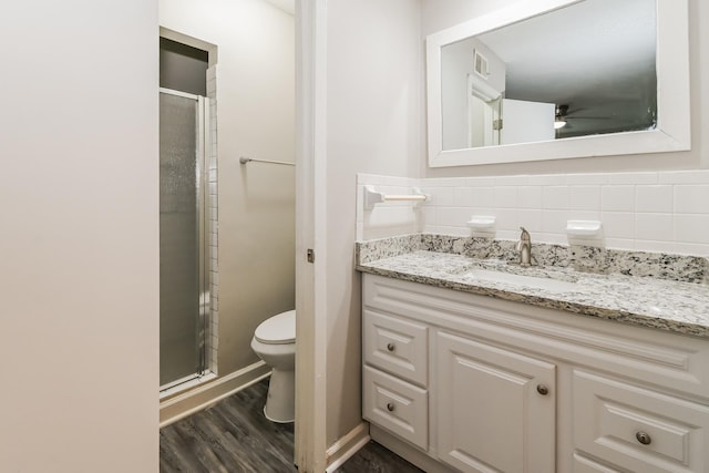 bathroom with tasteful backsplash, vanity, a shower with door, and toilet