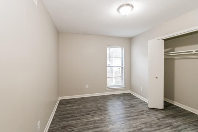 unfurnished bedroom featuring dark wood-type flooring, a textured ceiling, and a closet