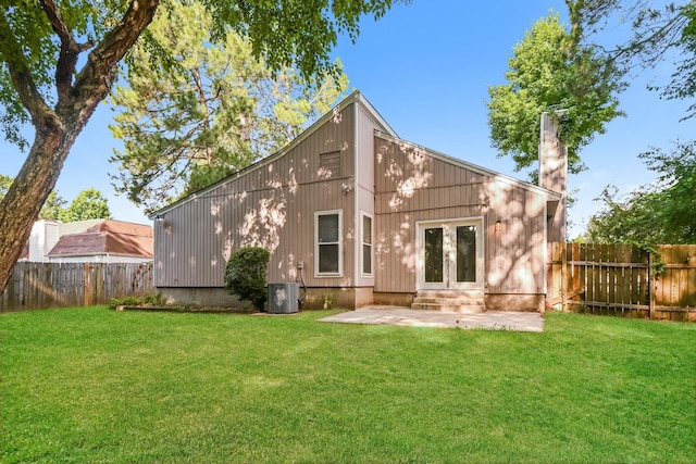 back of property with french doors, central air condition unit, a patio, and a lawn