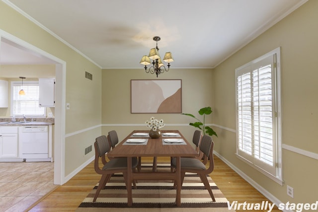 dining space with light wood-type flooring, sink, crown molding, and a notable chandelier