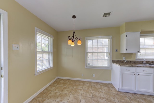 kitchen featuring light tile patterned floors, white cabinets, hanging light fixtures, and a notable chandelier