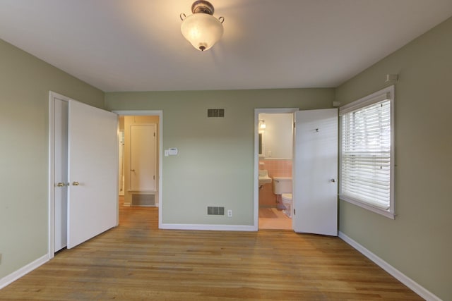 unfurnished bedroom with light wood-type flooring and ensuite bathroom