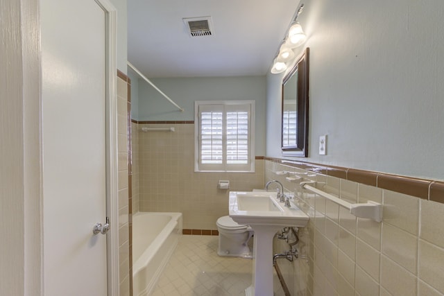 bathroom featuring toilet, tile walls, and washtub / shower combination