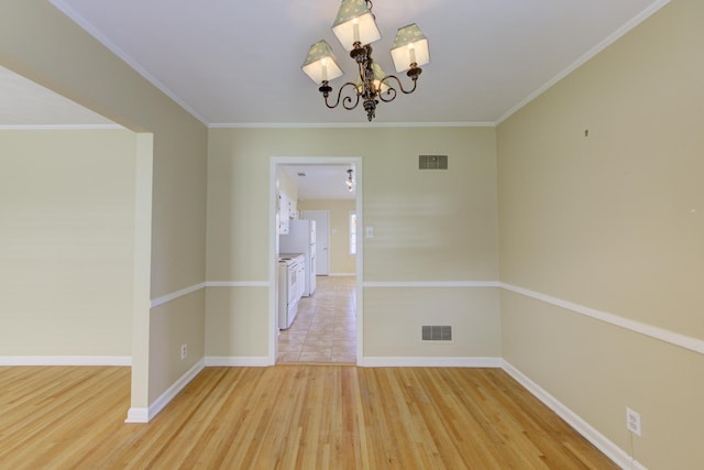 spare room featuring light hardwood / wood-style flooring, ornamental molding, and a notable chandelier