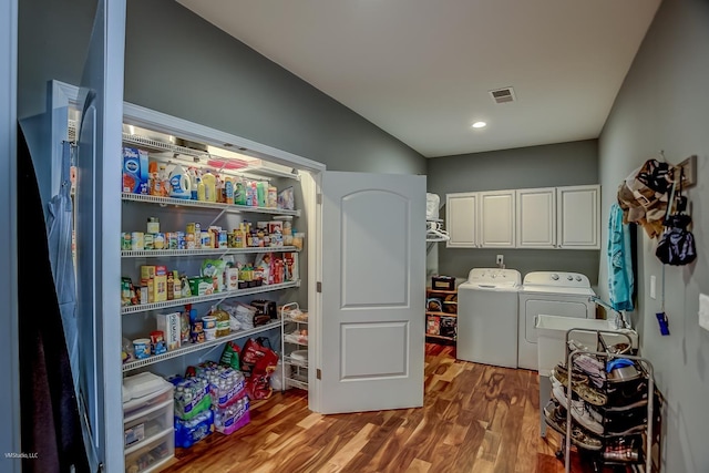 laundry room featuring washer and dryer, cabinets, and hardwood / wood-style flooring