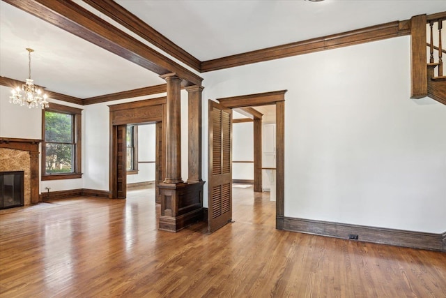 unfurnished living room featuring hardwood / wood-style floors, ornate columns, crown molding, and a high end fireplace