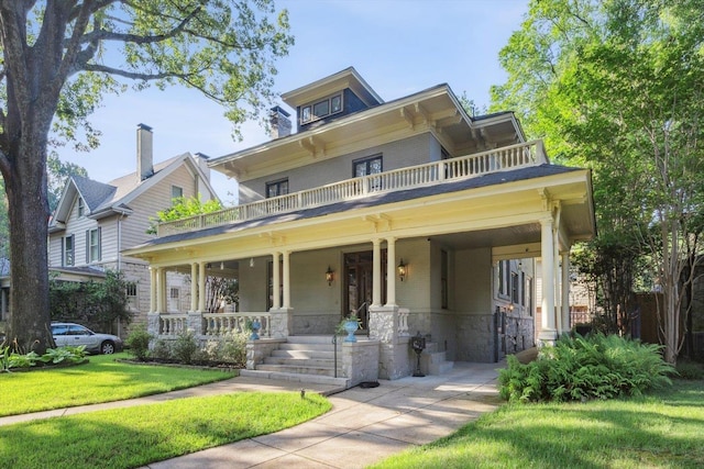 view of front of house featuring covered porch, a balcony, and a front lawn