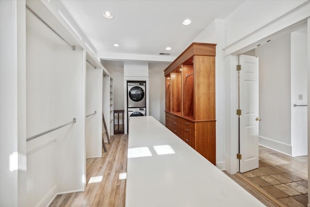 hall featuring light hardwood / wood-style floors and stacked washer and clothes dryer