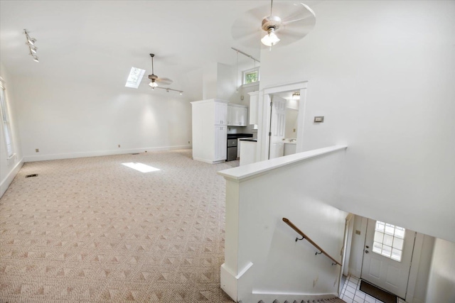 interior space with ceiling fan, plenty of natural light, a towering ceiling, and light carpet