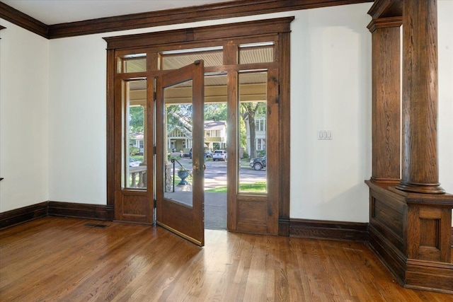 foyer entrance featuring french doors, hardwood / wood-style flooring, ornate columns, and crown molding