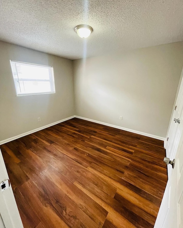 empty room featuring dark hardwood / wood-style flooring and a textured ceiling