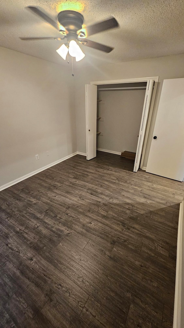 unfurnished bedroom with ceiling fan, dark hardwood / wood-style flooring, a closet, and a textured ceiling