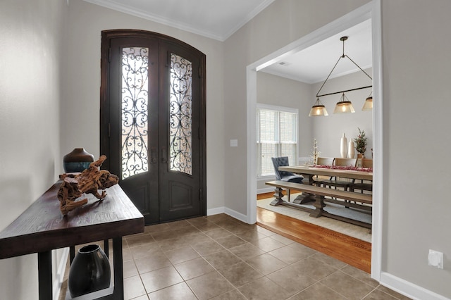 tiled entrance foyer with ornamental molding and french doors