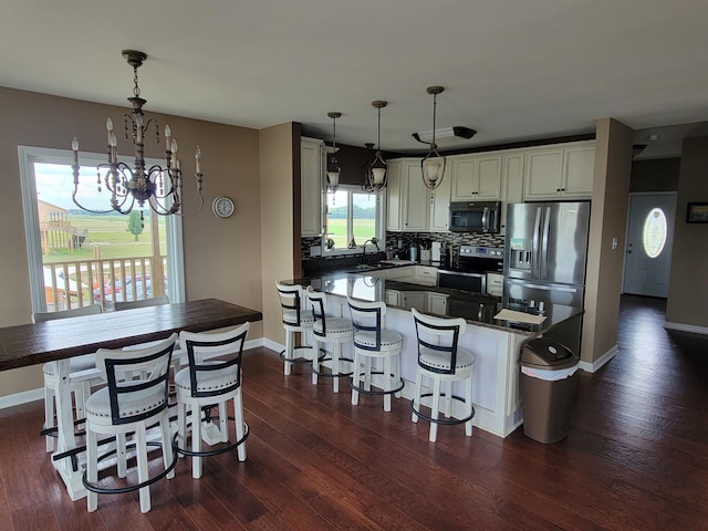 kitchen featuring pendant lighting, a kitchen breakfast bar, stainless steel appliances, dark hardwood / wood-style floors, and tasteful backsplash