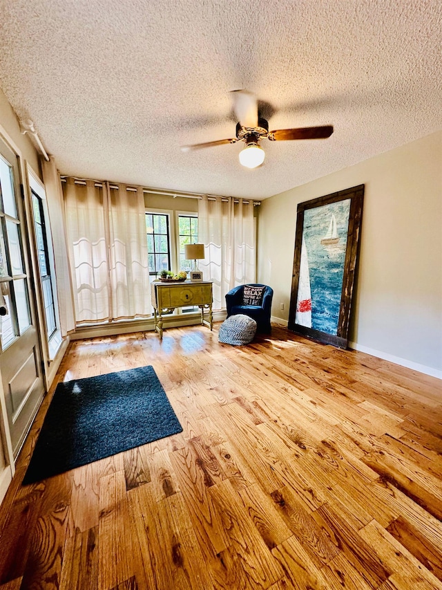 unfurnished room with ceiling fan, a textured ceiling, wood finished floors, and baseboards