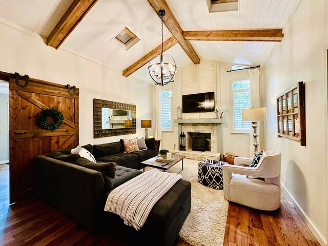 living room featuring vaulted ceiling with beams, an inviting chandelier, dark wood-type flooring, a barn door, and a stone fireplace