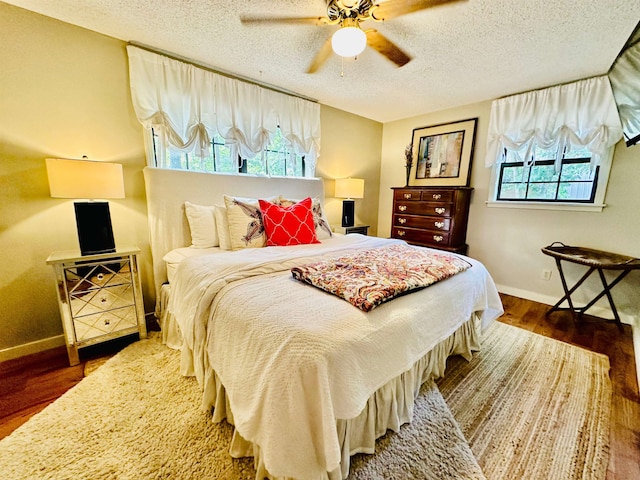 bedroom featuring a textured ceiling, ceiling fan, dark wood finished floors, and baseboards