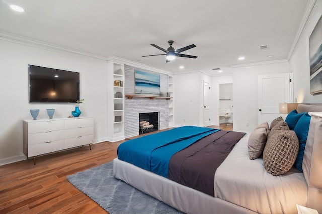 bedroom with crown molding, ensuite bathroom, ceiling fan, dark wood-type flooring, and a fireplace