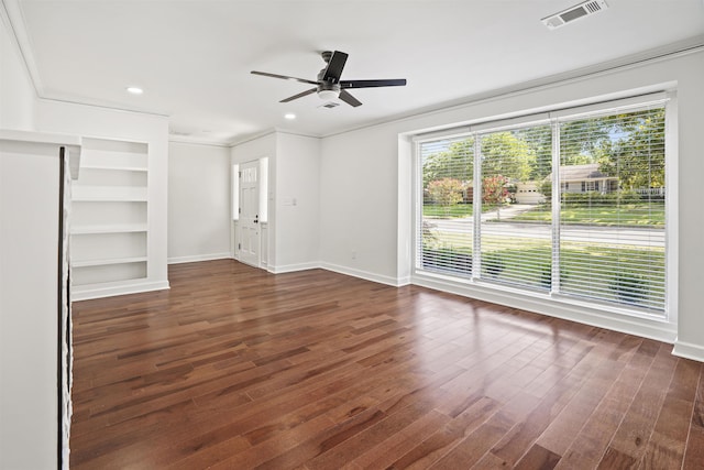 unfurnished living room with built in shelves, crown molding, ceiling fan, and dark hardwood / wood-style flooring