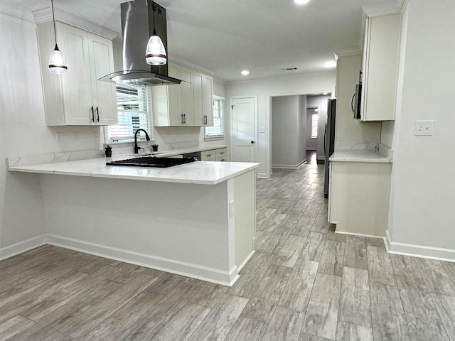 kitchen featuring white cabinets, island exhaust hood, hanging light fixtures, black fridge, and kitchen peninsula